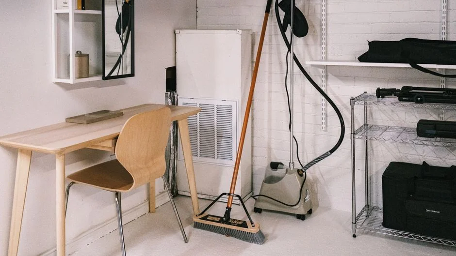 A professional cleaner in protective gear vacuuming the floor in a modern living room.